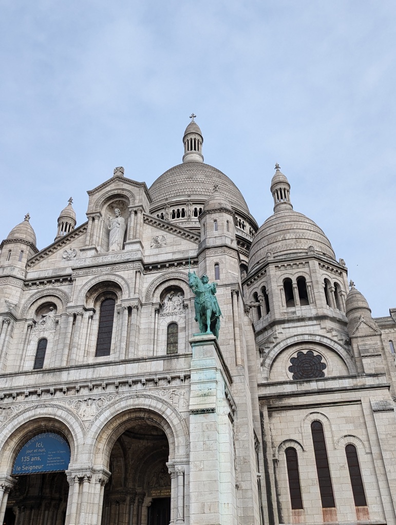 a detailed shot of the Sacre Coeur and the horsemen statue on the front entrance