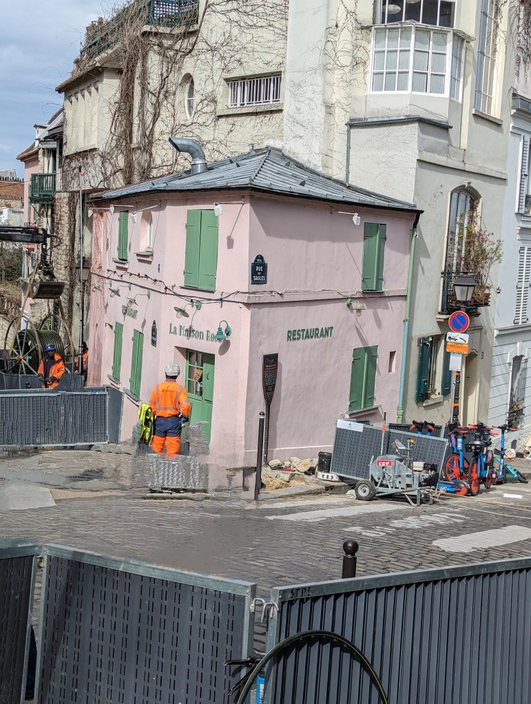 construction workers standing outside La Maison Rose in Paris with gates and dug up sidewalks
